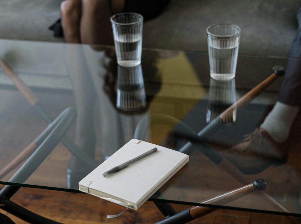 Close-up of a counseling session with two glasses of water and a notepad on a glass table.
